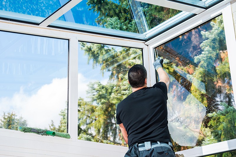 A man standing on ladder cleaning a set of windows